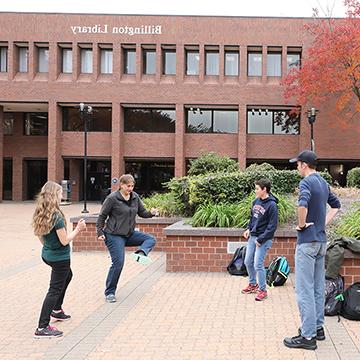 学生们在365体育主校区的比灵顿图书馆外玩曲棍球.